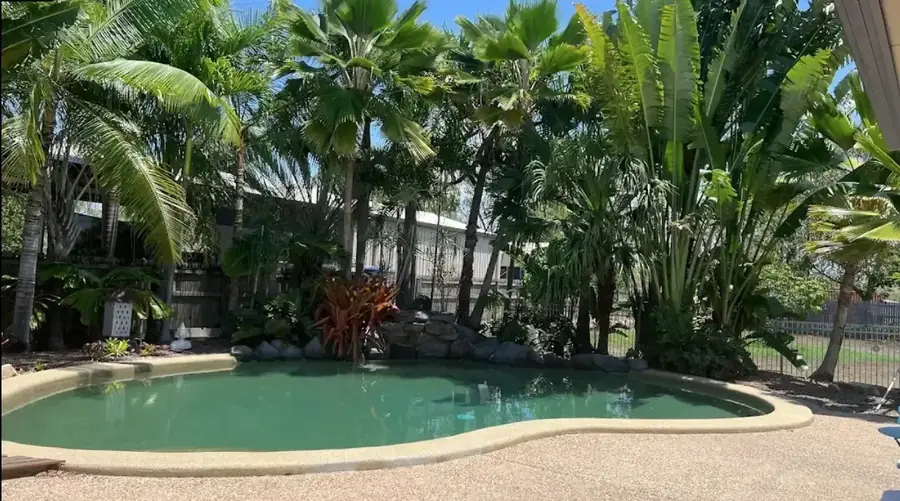 Landscaped backyard with established tropical trees around a pool